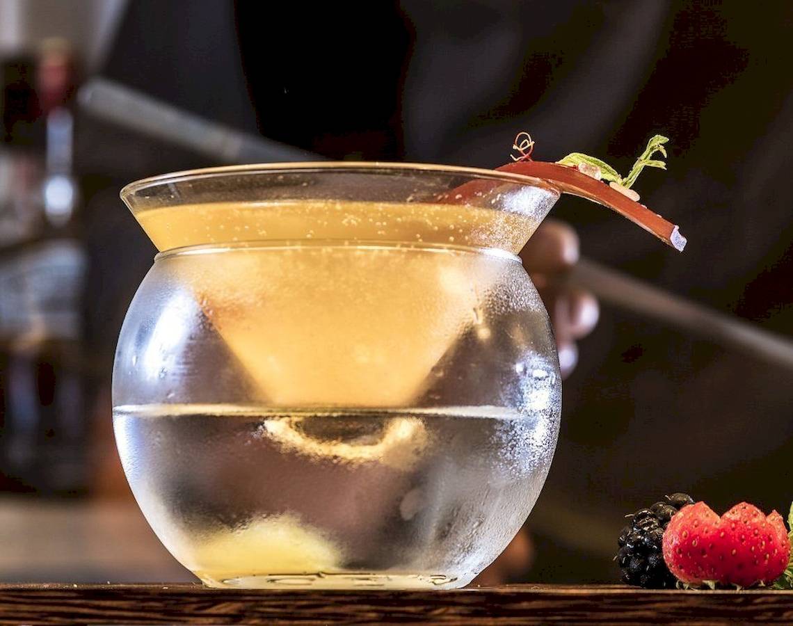 Ein Getränk in einem Glas mit Eis, dekoriert mit einer Fruchtscheibe und einigen Beeren.
