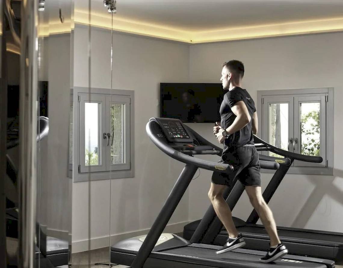 Mann im Fitnessraum der Katikies Villas Mykonos läuft auf einem Laufband.