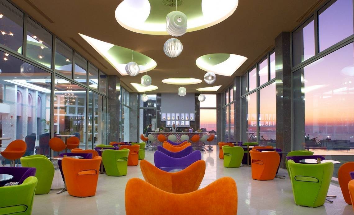 Hotellobby des Atrium Platinum Luxury Resort Hotel & Spa mit farbenfrohen Sesseln und einer Bar im Hintergrund.