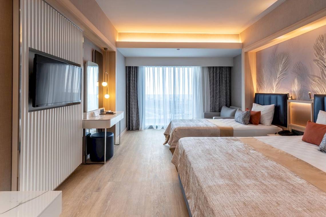 Ansicht eines Doppelzimmers im Lago Hotel mit zwei Betten, Fernseher und Schreibtisch.