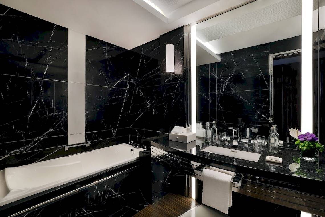 Schwarzes Marmorbadezimmer im Marriott Resort Palm Jumeirah, Dubai, mit Badewanne, Waschbecken und Spiegel.