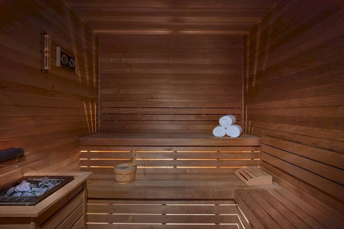 Sauna im Marriott Resort Palm Jumeirah mit Holzwänden, Bänken und aufgerollten Handtüchern.