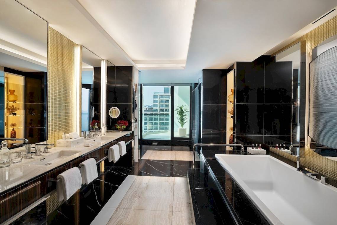 Luxuriöses Badezimmer im Marriott Resort Palm Jumeirah, Dubai mit schwarzen Marmorwänden und weißen Armaturen.
