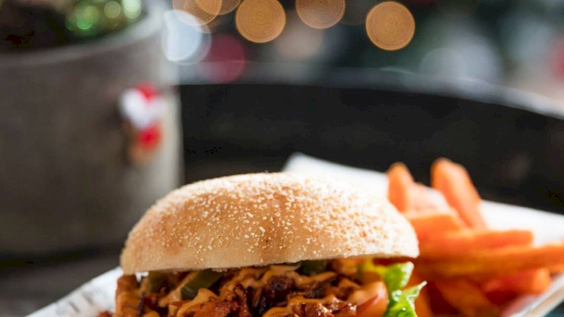Ein Burger mit Beilagen auf einem Teller im Tower Hotel, London.