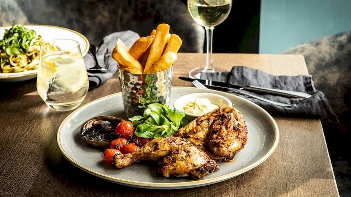 Ein Tisch im Tower Hotel in London mit einem Teller gebratenem Hähnchen, Pommes, Tomaten und Salat.