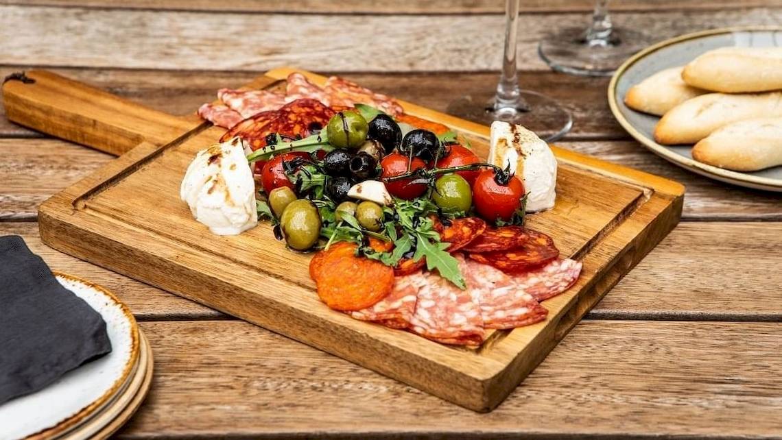 Ein Holzschneidebrett mit verschiedenen Delikatessen auf einem Holztisch.