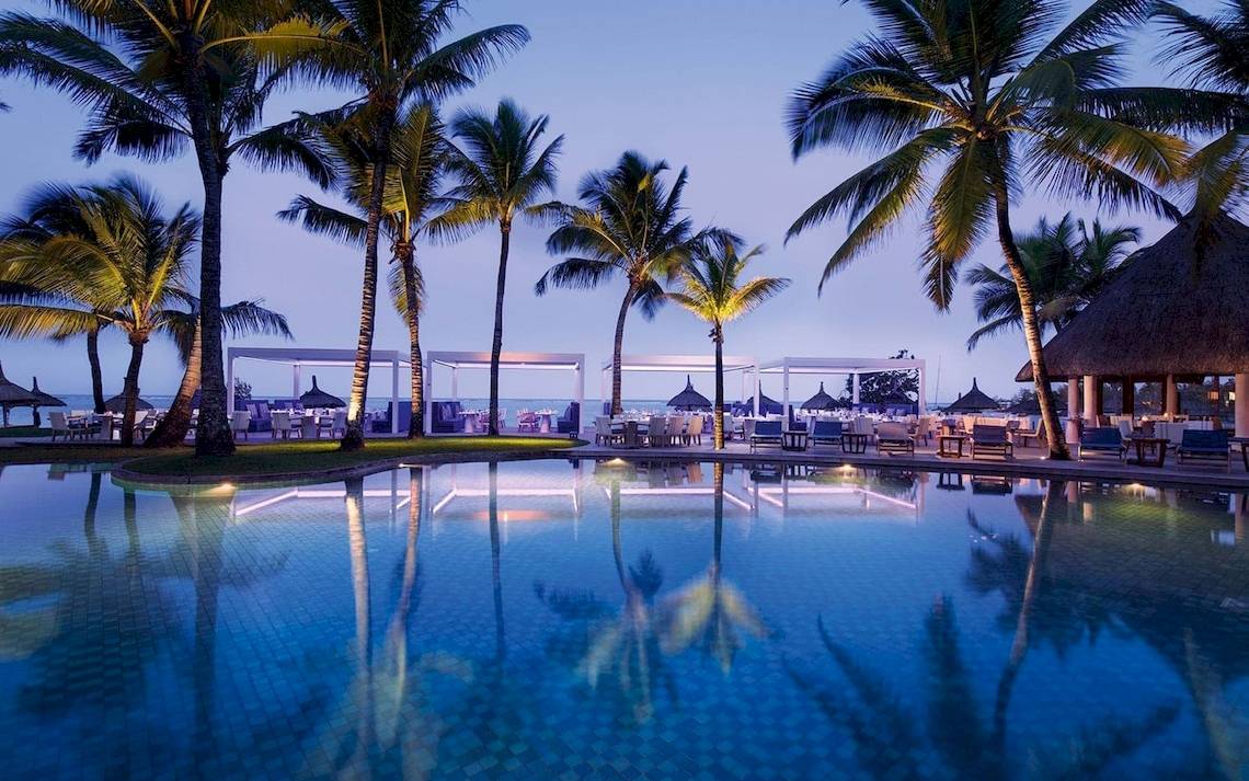 Abendlicher Poolbereich des Constance Ephelia Mahe Seychelles mit Palmen und Sitzgelegenheiten.