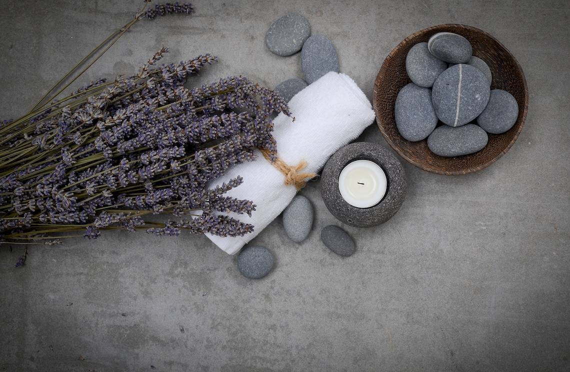 Lavendel, Handtuch, Kerze und Steine auf Beton