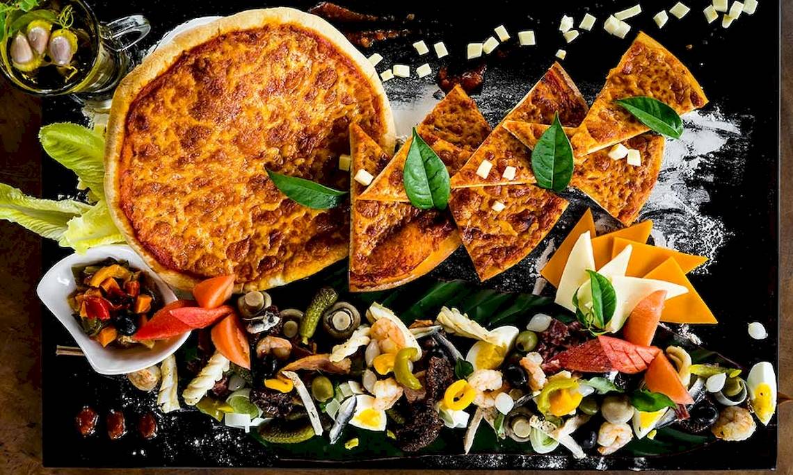 Eine kulinarische Speiseplatte mit einer Pizza und verschiedenen Meeresfrüchten im Le Duc de Praslin Hotel & Villas.