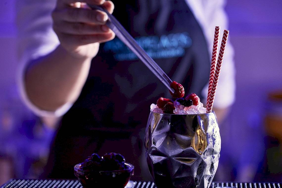 Barkeeper im Archipelagos Hotel, der einen Cocktail in einem kristallenen Glas zubereitet.