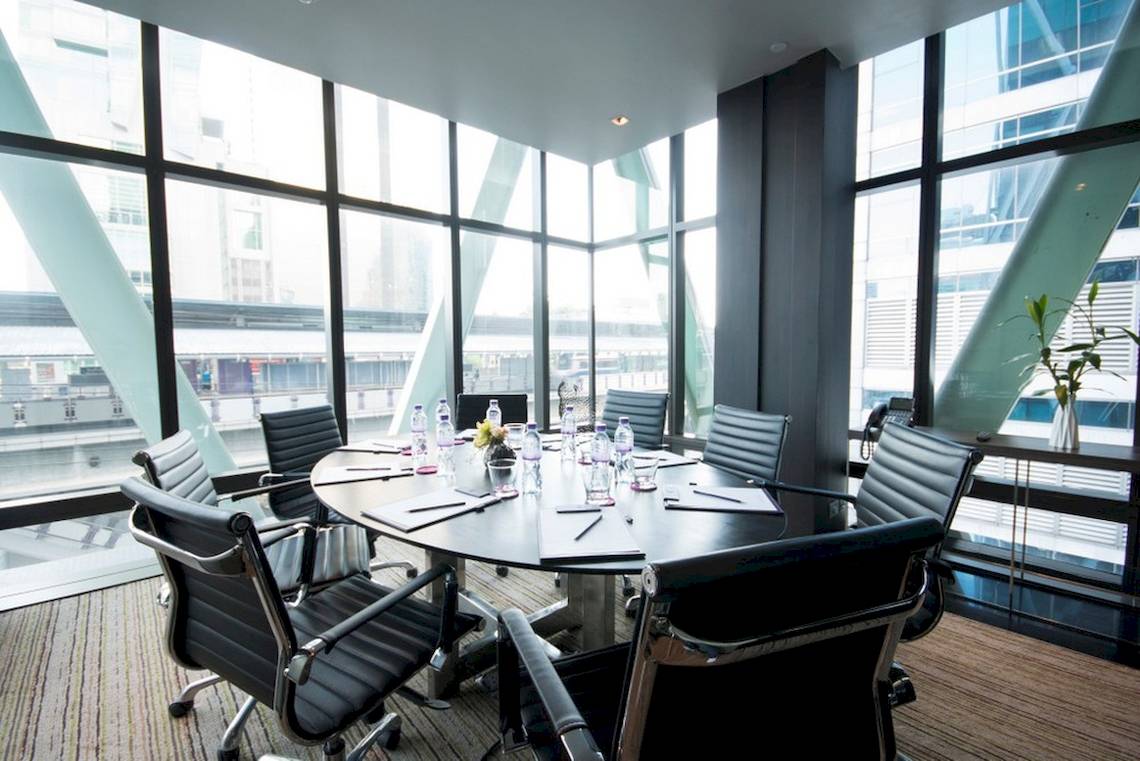Konferenzraum im Mode Sathorn Hotel mit ovalem Tisch, schwarzen Lederstühlen und großen Fenstern.