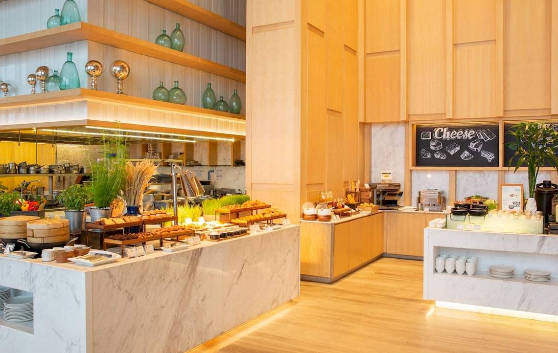 Frühstücksbuffet im AVANI+ Riverside Bangkok mit verschiedenen Gerichten und Utensilien.