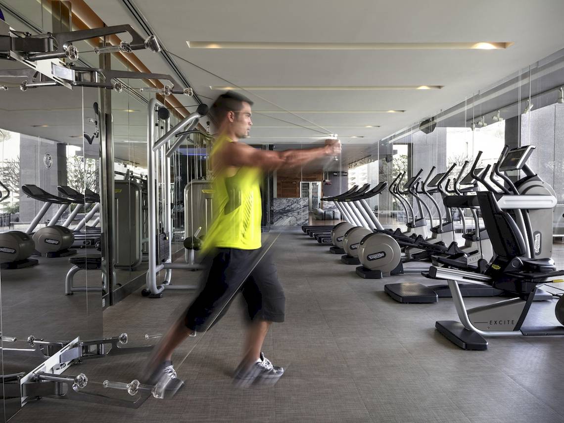 Fitnessstudio im SO/ Bangkok mit einem Mann, der Übungen mit einem Widerstandsband macht.
