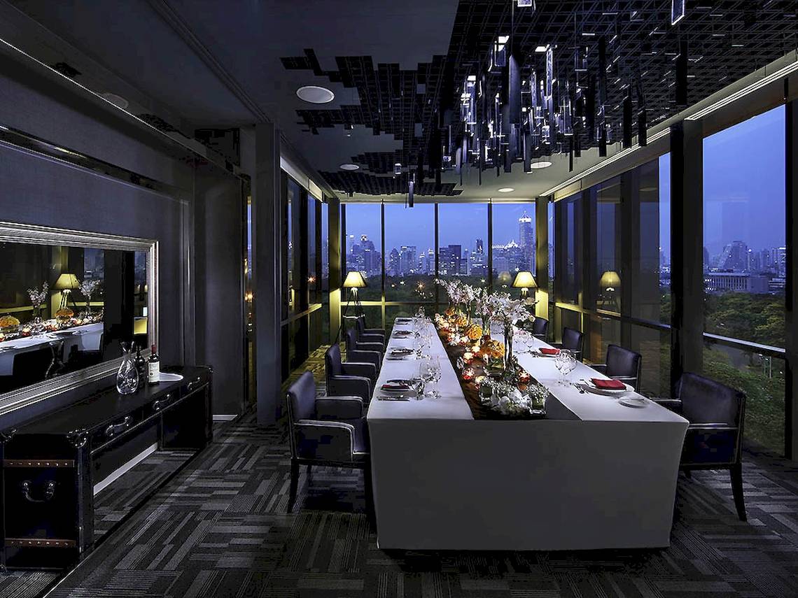 SO/ Bangkok Hotel Essen Bereich mit langem Tisch und Blick auf die Stadt.