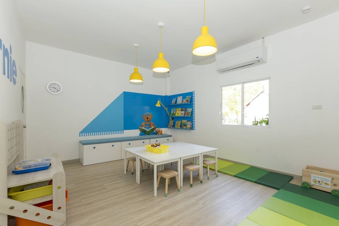 Kinderzimmer im Sunwing Bangtao Beach Hotel mit blauen und weißen Wänden, gelben Lampen und einer Bücherwand.