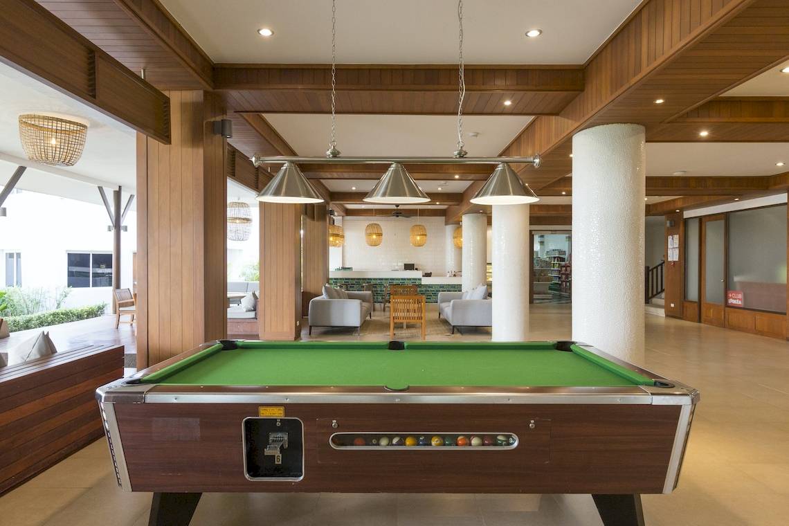Ein Pooltisch im Innenbereich eines Hotels, umgeben von Möbeln und Holzelementen.