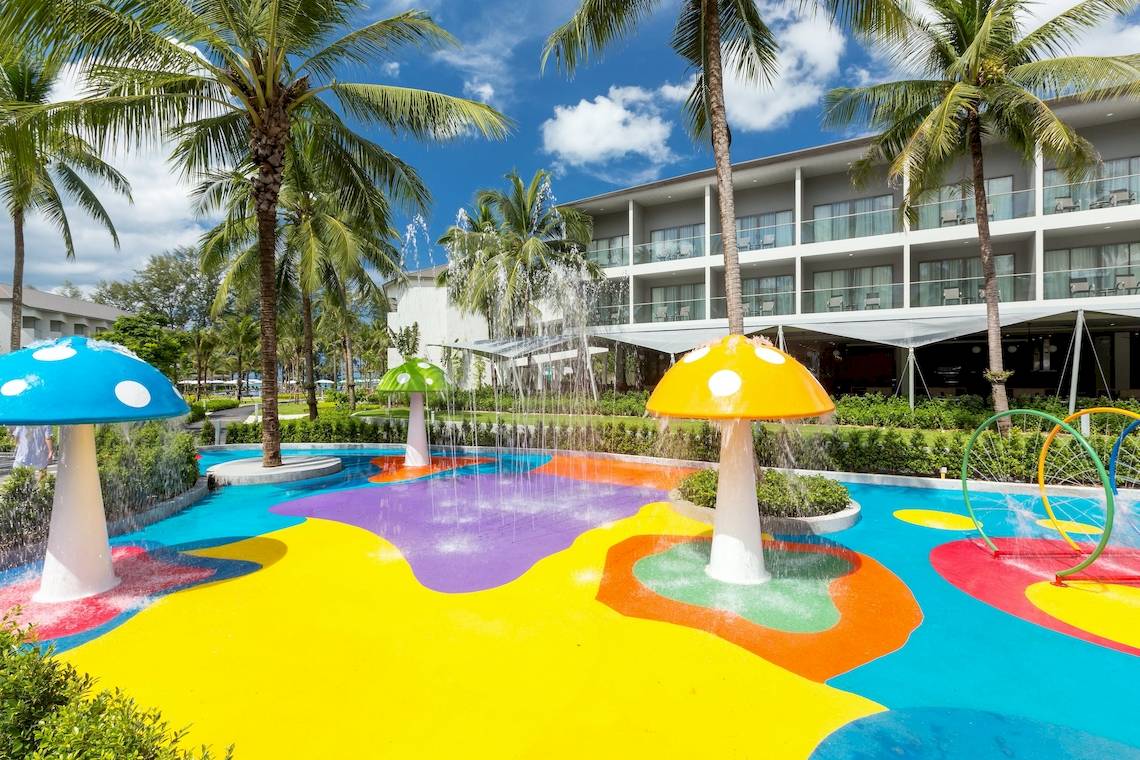 Außenbereich des X10 Khaolak Resorts mit buntem Wasserspiel und Palmen.
