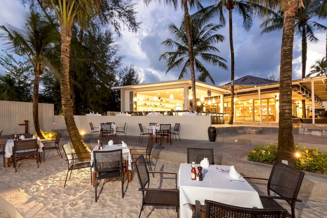 Alfresco-Essbereich des X10 Khaolak Resorts mit Tischen, Stühlen und Palmen