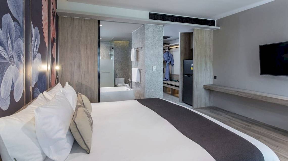 Schlafzimmer im La Flora Khao Lak Hotel mit Bett, Badezimmer und Fernseher