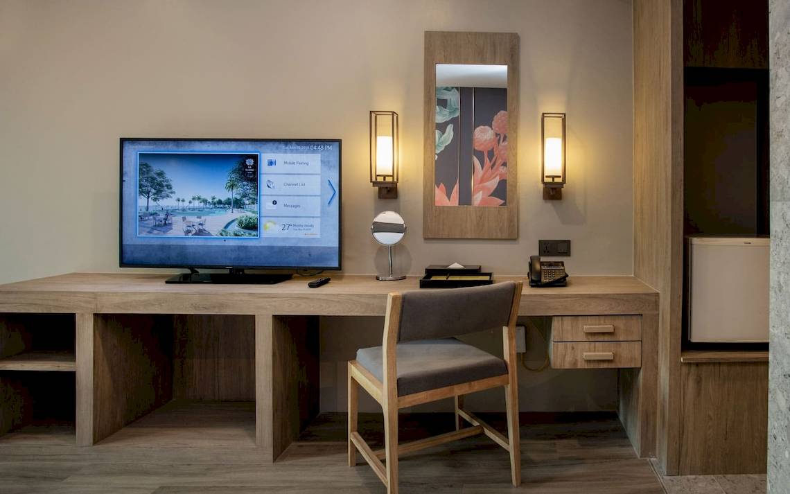 Hotelzimmer im La Flora Khao Lak mit Schreibtisch, Fernseher und Wandlampen