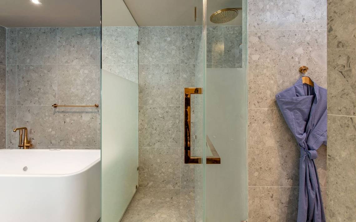 Badezimmer im La Flora Khao Lak Hotel mit Badewanne und Glasdusche.