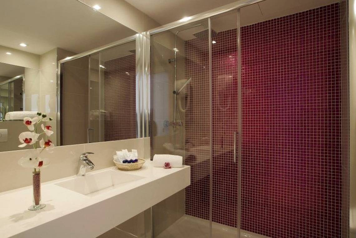 Badezimmer im Argos Hotel mit roten Fliesen und einem Spiegel.