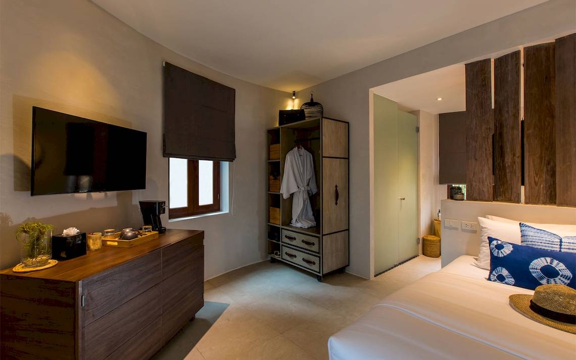 Ein Zimmer im Bangsak Village Hotel mit einem Bett, Fernseher, Kleiderschrank und Dekor.