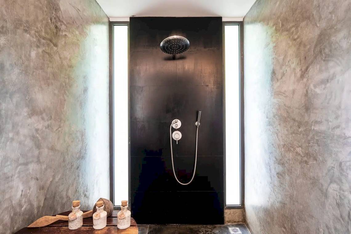 Dusche im TreeHouse Villas Koh Yao mit schwarzem Hintergrund und Marmorwänden.
