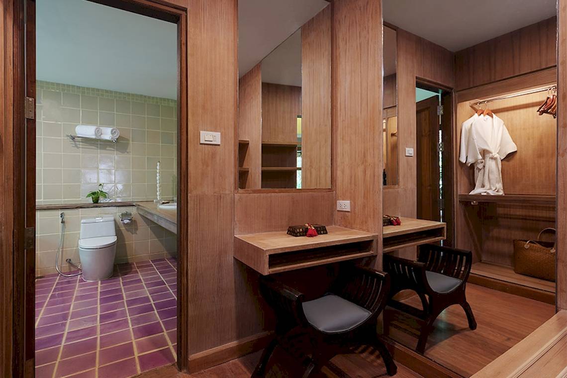 Badezimmer des Khaolak Paradise Resort mit Holzwänden, einem Toilettensitz, Waschbecken und Spiegeln.
