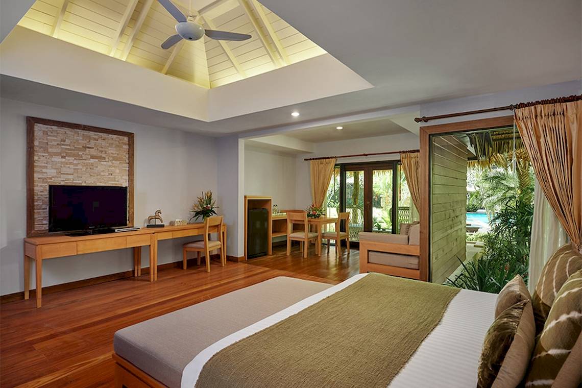 Innenansicht eines Zimmers im Khaolak Paradise Resort mit Holzboden, großem Bett und Fernseher.