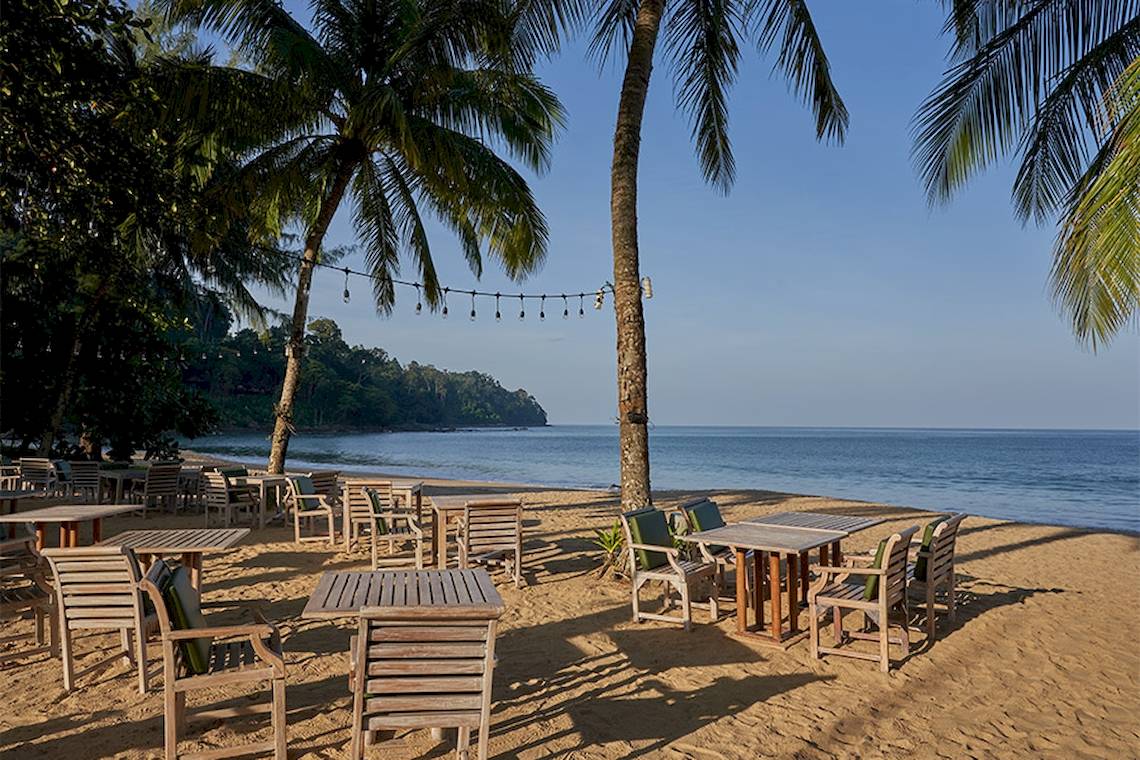 Sitzplätze am Strand des Khaolak Paradise Resorts mit Blick auf das Meer und Palmen.