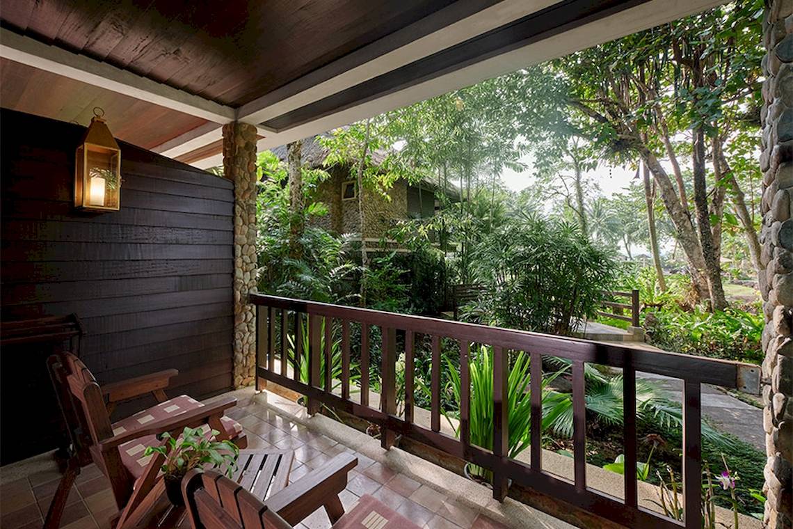 Blick vom Balkon des Khaolak Paradise Resorts auf den Garten und ein traditionelles Haus.