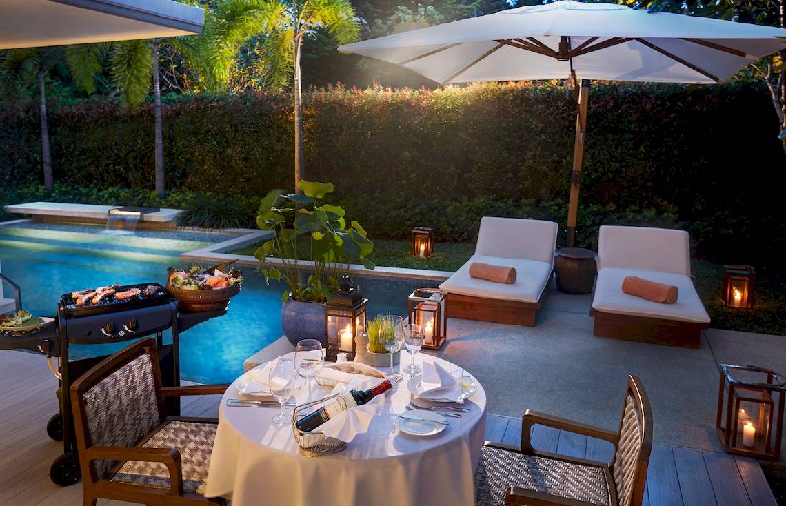 Poolseite-Dinnerbereich im Santiburi Koh Samui mit Tisch, Grill und Lounge-Möbeln.