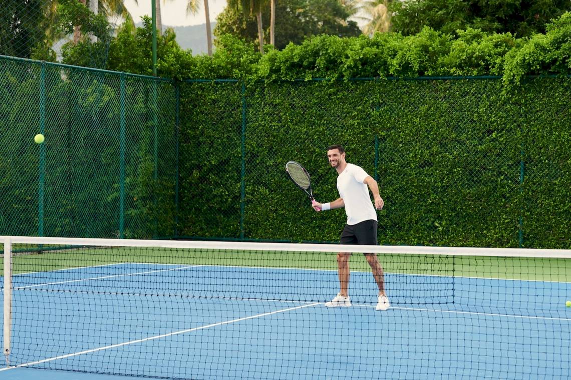 Tennisspieler auf blauem Platz im Hotel Santiburi Koh Samui