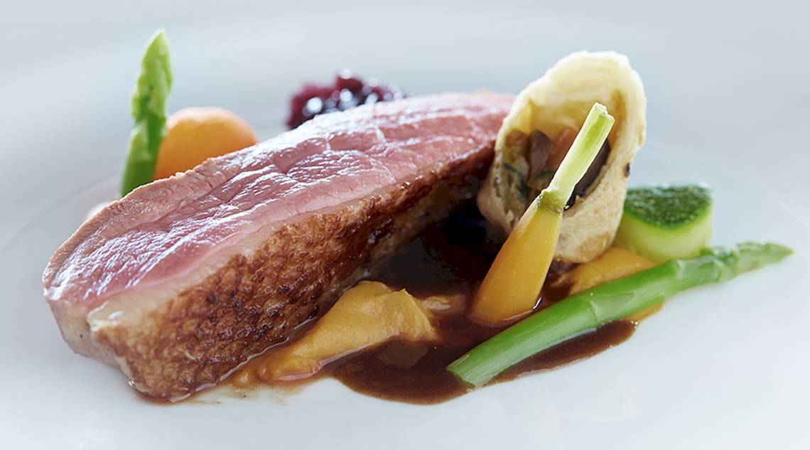Ein Gericht im Bo Phut Resort & Spa mit gebratenem Fleisch, Gemüse und Soße auf einem weißen Teller.