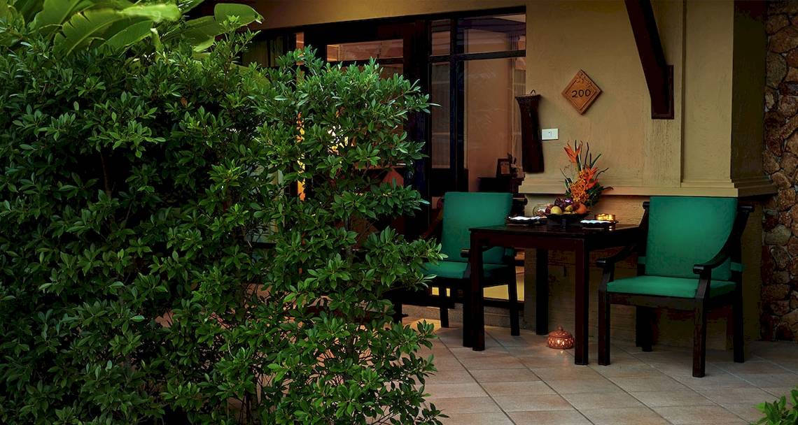 Terrasse des Bo Phut Resort & Spa mit grünen Stühlen und Tisch, dekoriert mit Früchten und Lampion.