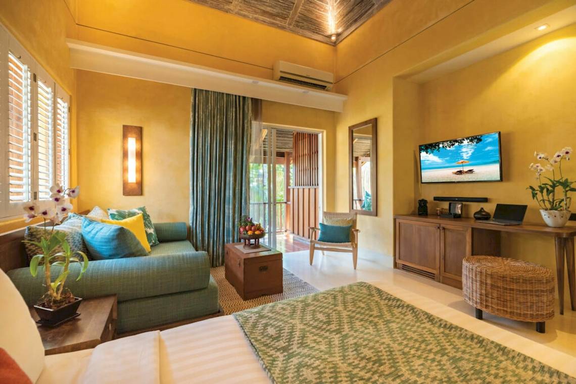 Hotelzimmer im Buri Rasa Village Samui mit einem Bett, einem Fernseher, einer Couch und einem Tisch