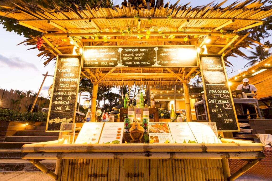 Cocktailbar in einer Bambushütte im Buri Rasa Village Samui mit Menüs und Getränkeangeboten.