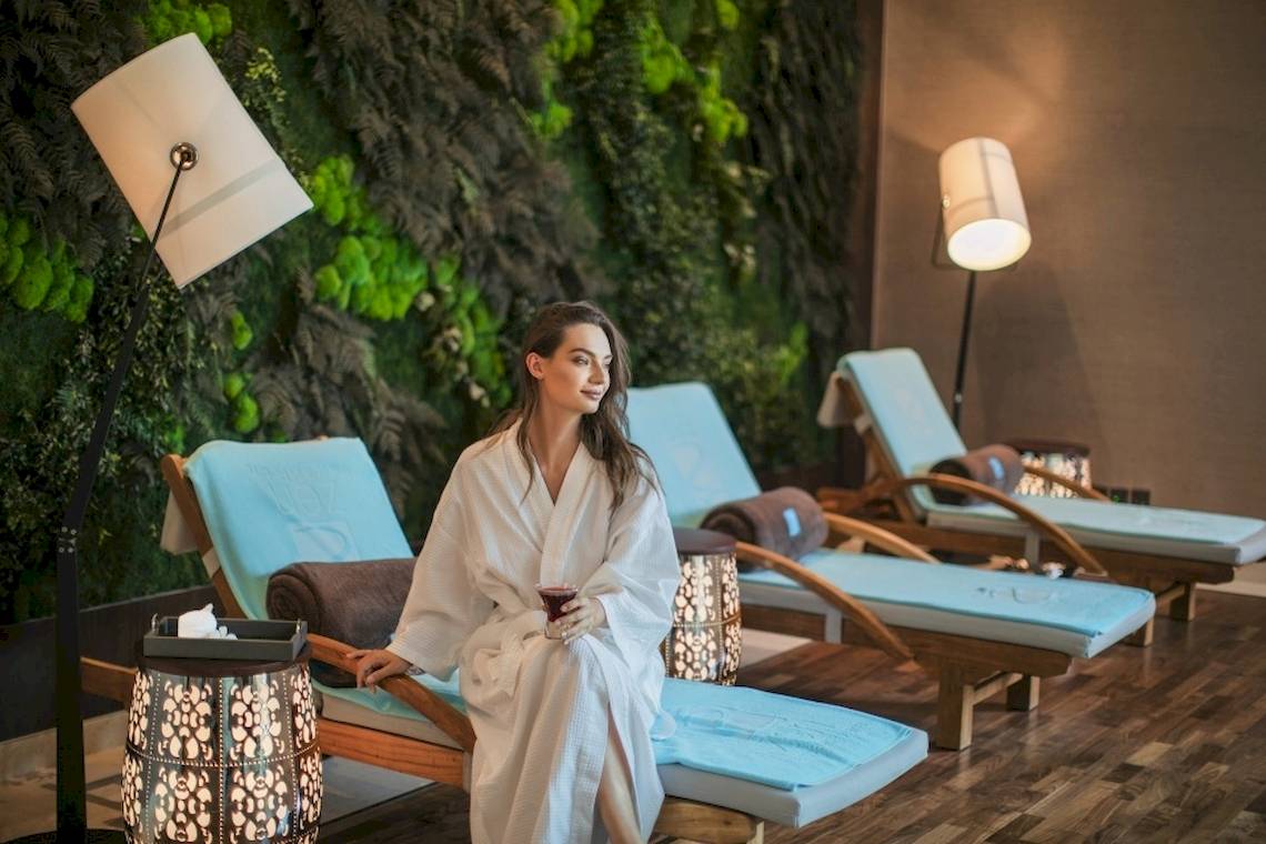 Frau in einem weißen Bademantel sitzt in einem Spa-Bereich von Saadiyat Rotana Resort & Villas