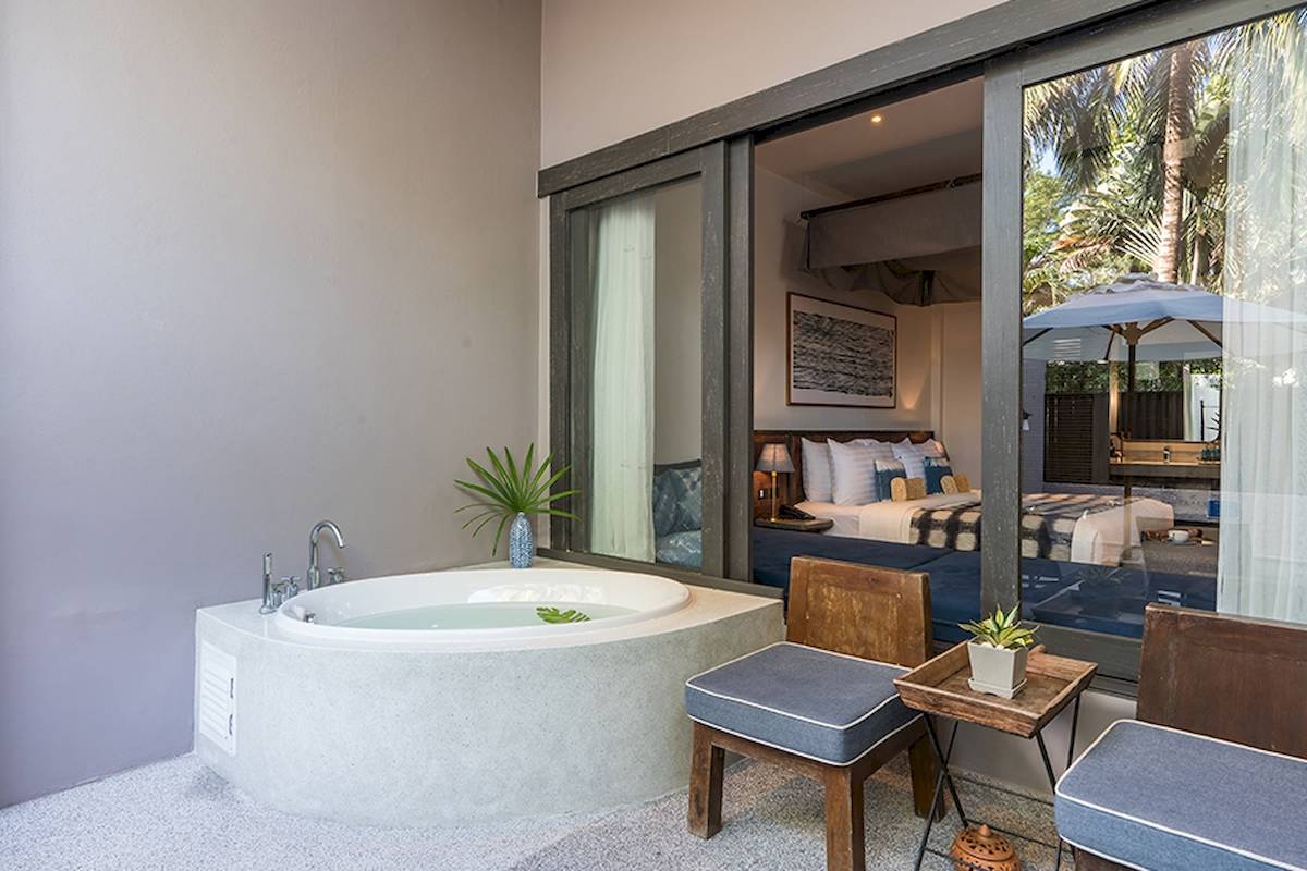 Ein Badezimmer mit einer Außenbadewanne und Blick auf ein Schlafzimmer im Peace Resort.