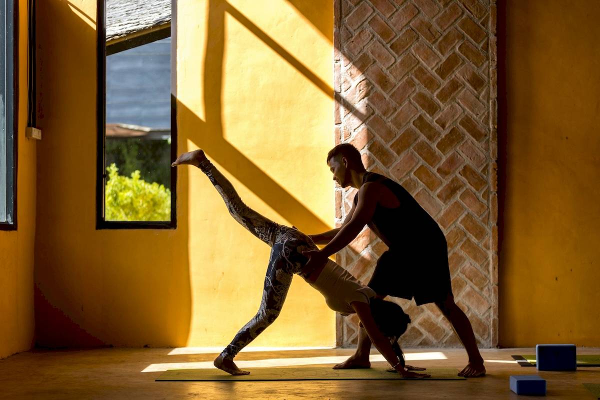 Ein Mann hilft einer Frau bei einer Yoga-Übung im Anana Ecological Resort Krabi.
