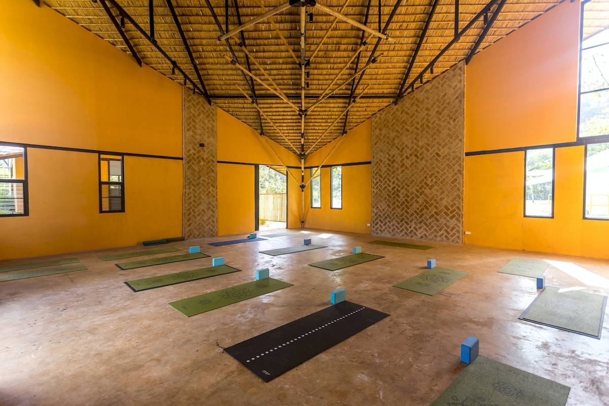 Yogaraum im Anana Ecological Resort Krabi mit gelben Wänden und Bambusdach.
