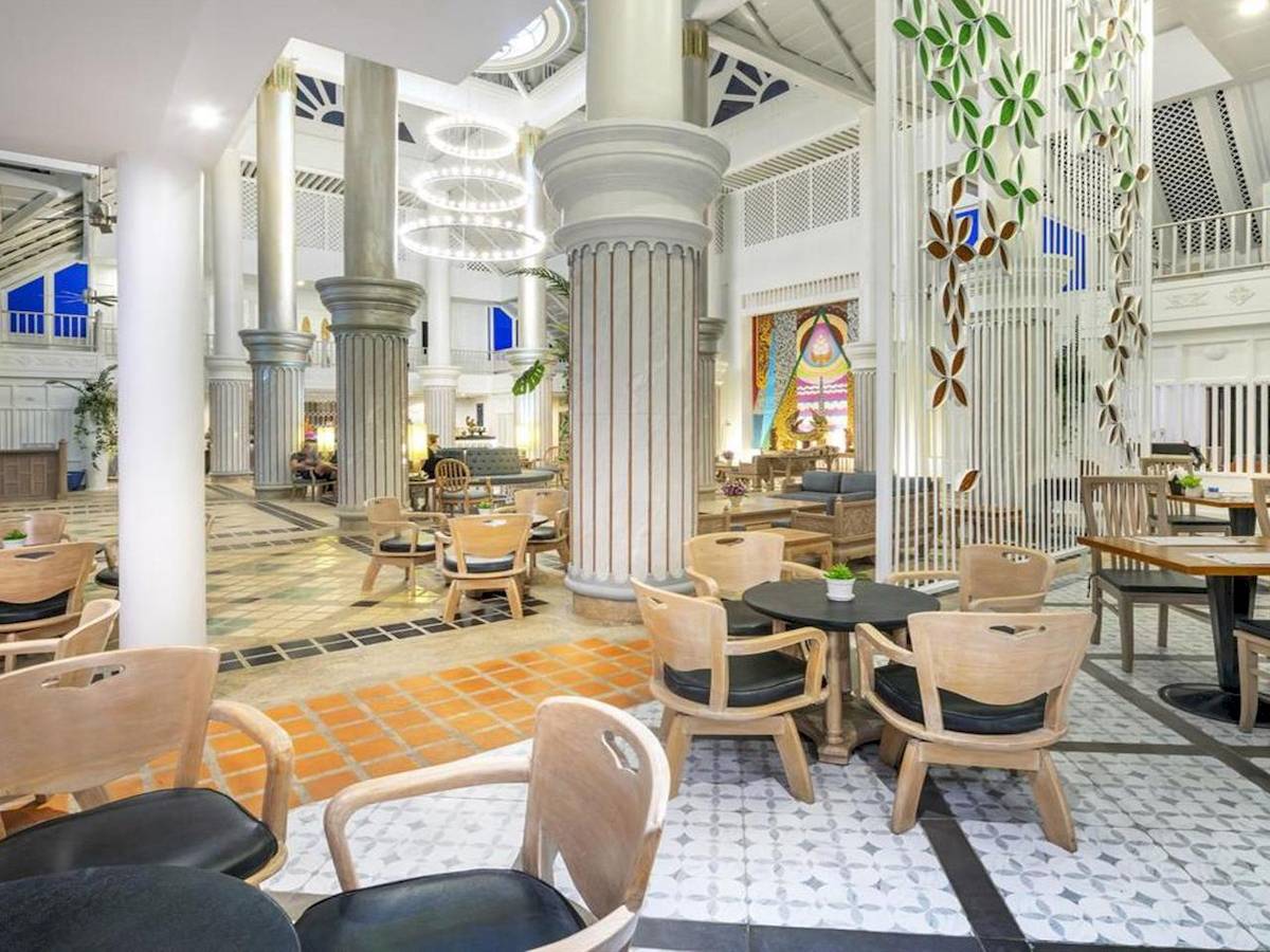 Interieur des Chada Thai Village Resorts mit Säulen, Tischen und Stühlen.