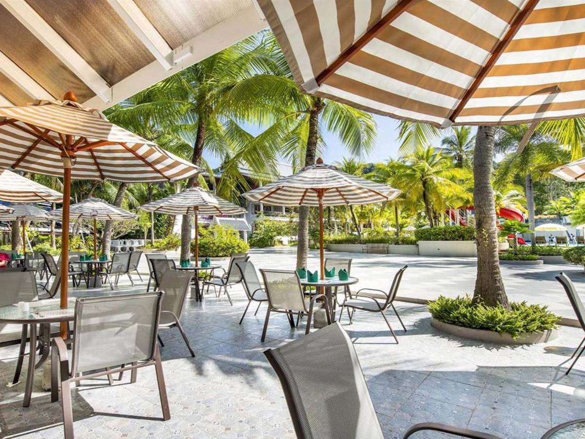 Terrasse des Chada Thai Village Resorts mit gesäumten Tischen und Stühlen.