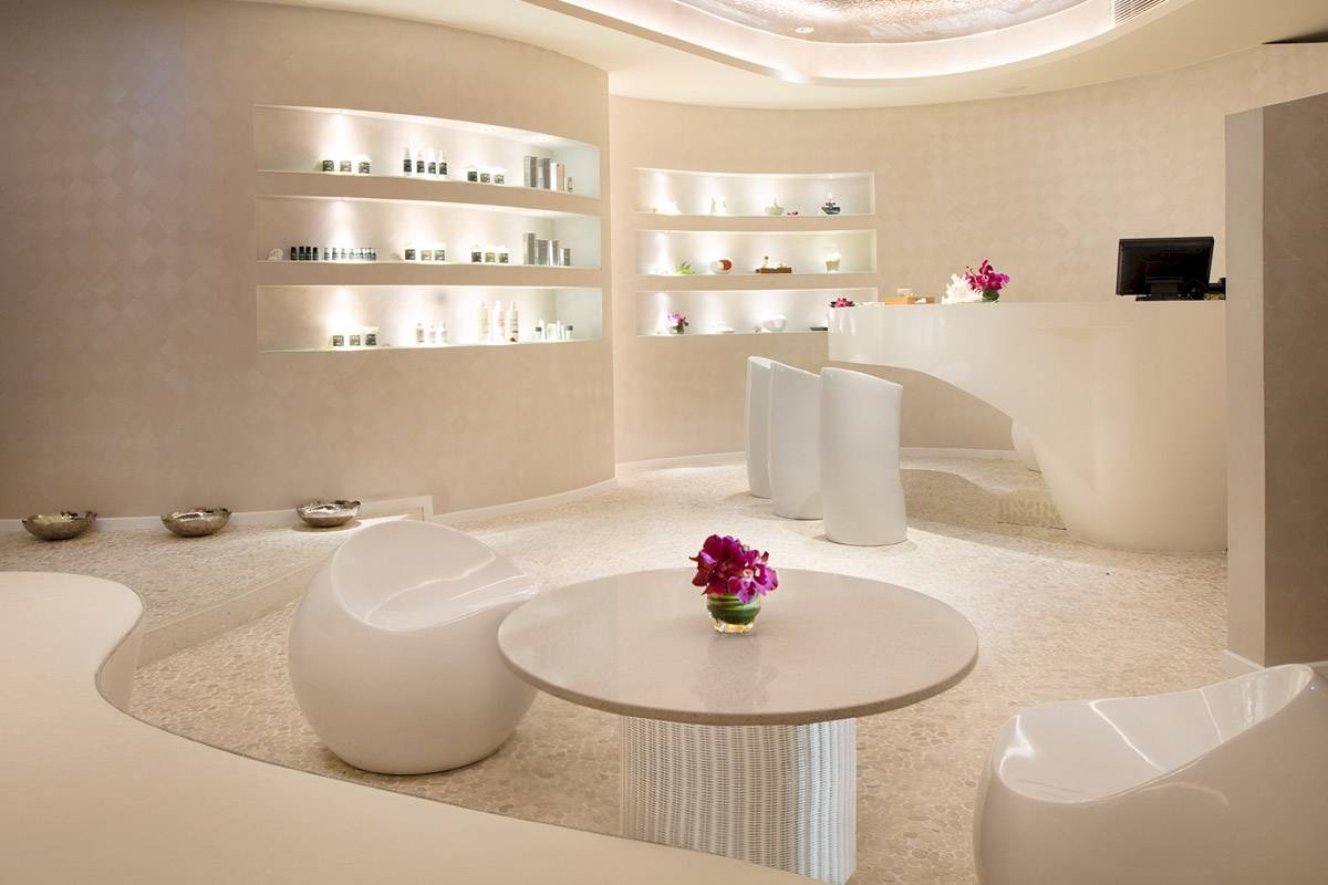Innenansicht des ShellSea Krabi Hotels mit weißen Möbeln, einem Tisch mit Blumen und Regalen.