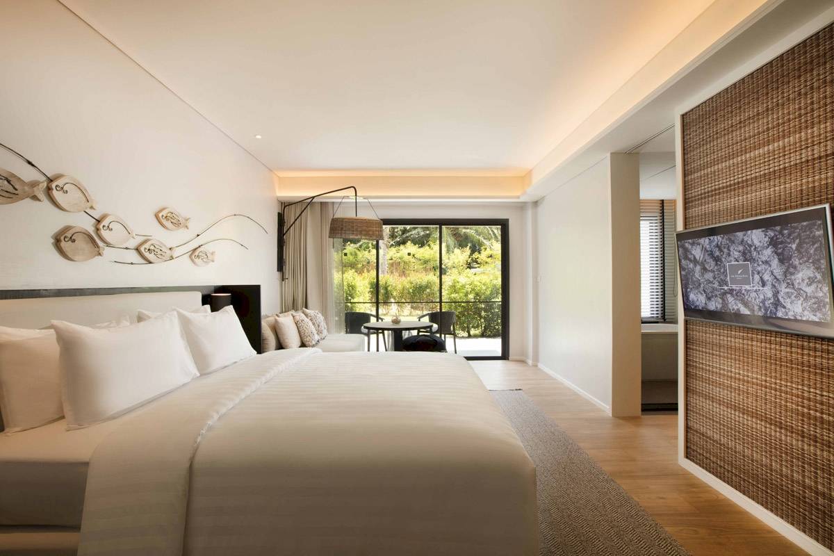Schlafzimmer im The ShellSea Krabi mit Bett, Fenstern und Fernseher.