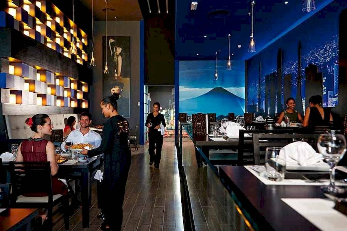 Restaurantszene im Riu Palace Costa Rica mit Gästen, Kellnerin und Einrichtung.