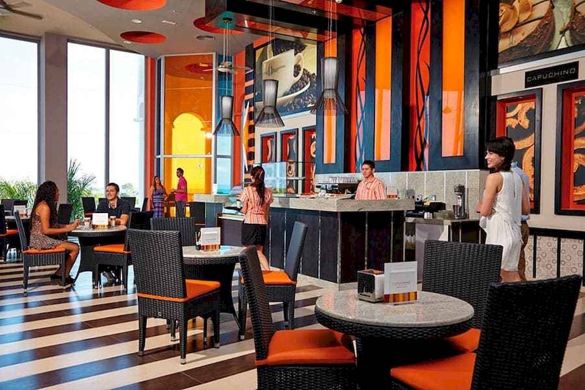 Innenansicht der Bar im Riu Palace Costa Rica Hotel mit Gästen und Möbeln.