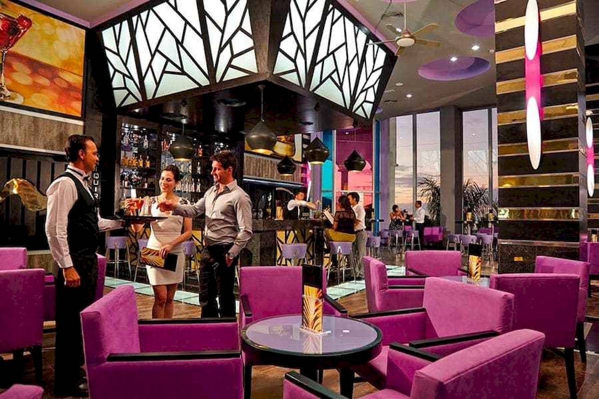 Hotelbar des Riu Palace Costa Rica mit Gästen und Barkeepern, die Getränke servieren.