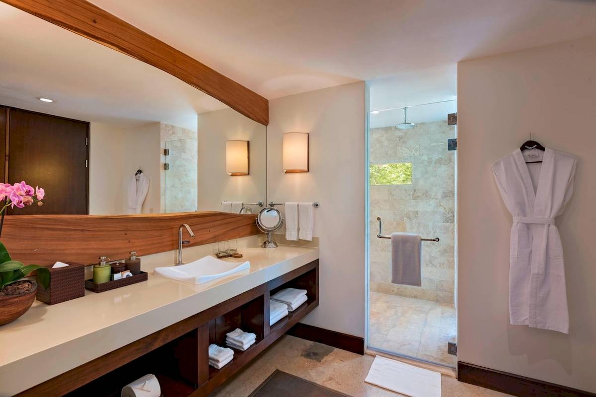 Ein Badezimmer mit einem großen Spiegel, einer Dusche und einem Waschbecken im El Mangroove, Autograph Collection Hotel.